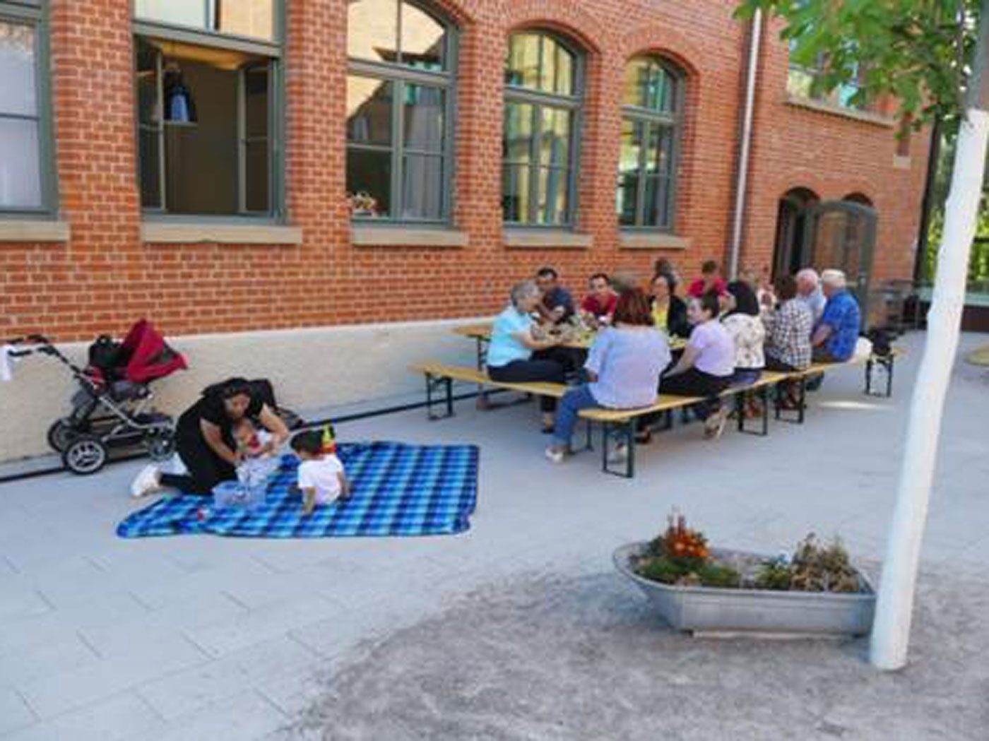 Das Foto zeigt eine Gruppe Menschen an einem Tisch und links danben eine Frau mit zwei Kindern auf einer Decke. Die Veranstaltung gehört zum Projekt "Fit im Kopf" in Neckarweihingen.