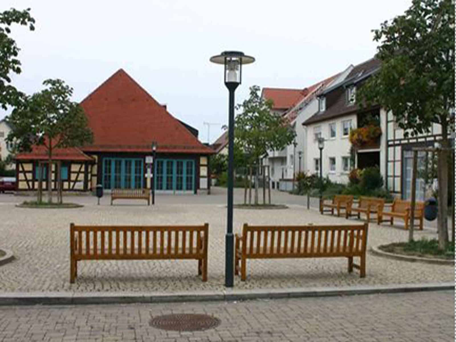Das Foto zeigt den Kelterplatz in Eglosheim. Um den Platz stehen einige Holzbänke und Bäume sind gepflanzt.